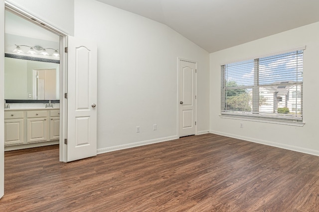 unfurnished bedroom with dark hardwood / wood-style flooring, lofted ceiling, sink, and ensuite bath