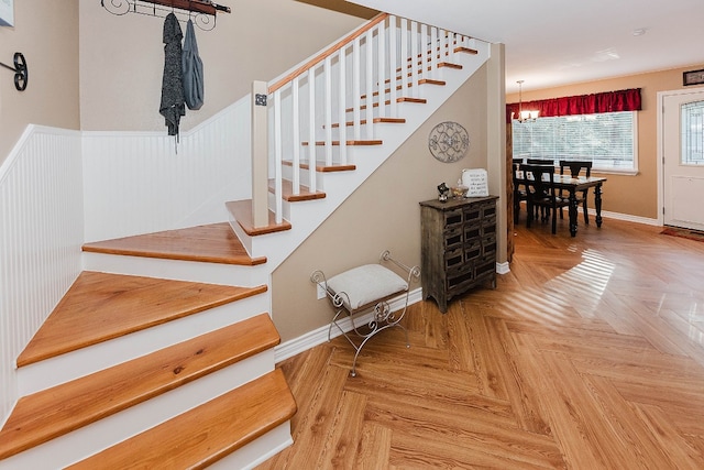 stairs with a chandelier and parquet flooring