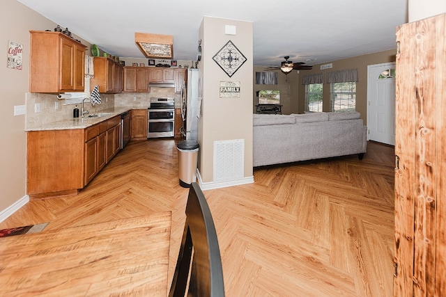 kitchen featuring appliances with stainless steel finishes, decorative backsplash, light parquet floors, ceiling fan, and sink