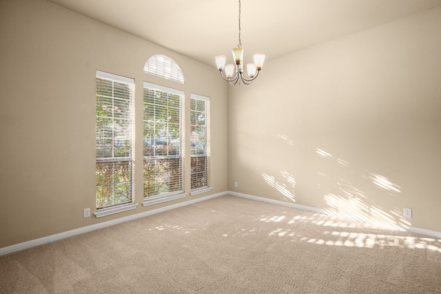 carpeted spare room with a chandelier