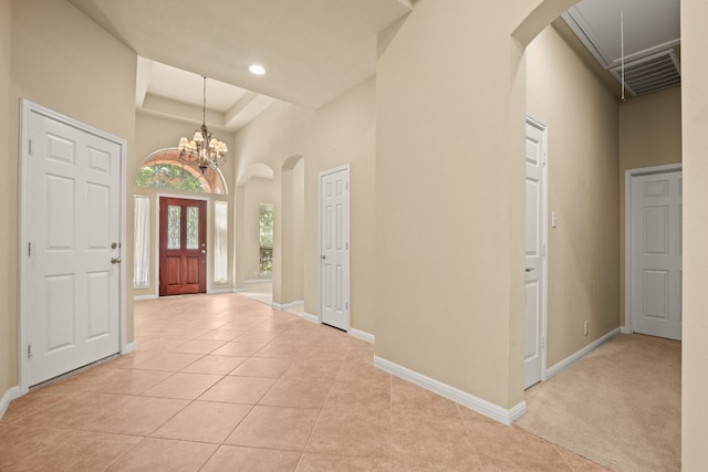 foyer entrance with a high ceiling, an inviting chandelier, and light colored carpet