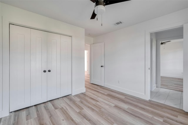 unfurnished bedroom with light wood-type flooring, ceiling fan, and a closet