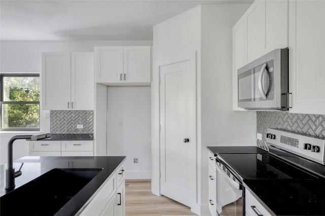 kitchen featuring backsplash, appliances with stainless steel finishes, sink, white cabinets, and light hardwood / wood-style flooring