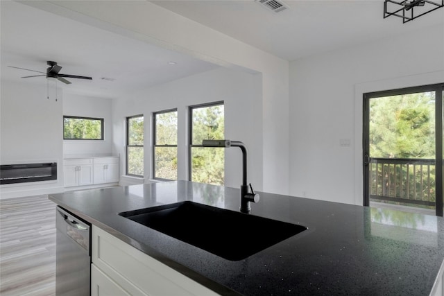 kitchen featuring white cabinetry, sink, stainless steel dishwasher, ceiling fan, and light hardwood / wood-style flooring