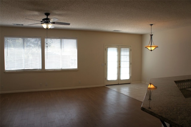 unfurnished living room with ceiling fan, hardwood / wood-style flooring, and a textured ceiling