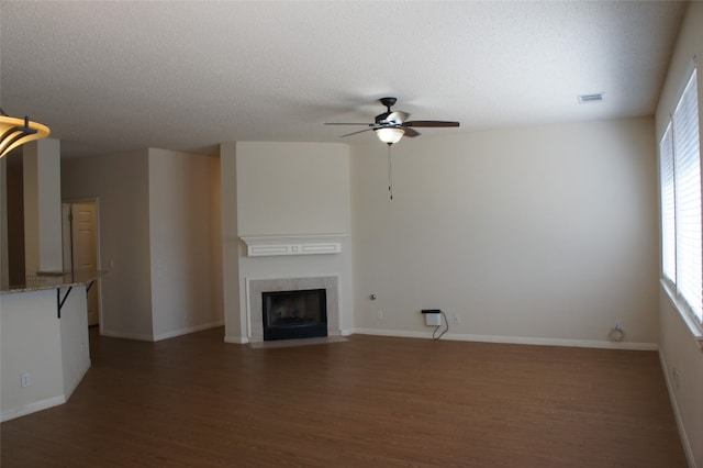 unfurnished living room with a textured ceiling, a tiled fireplace, and dark hardwood / wood-style flooring