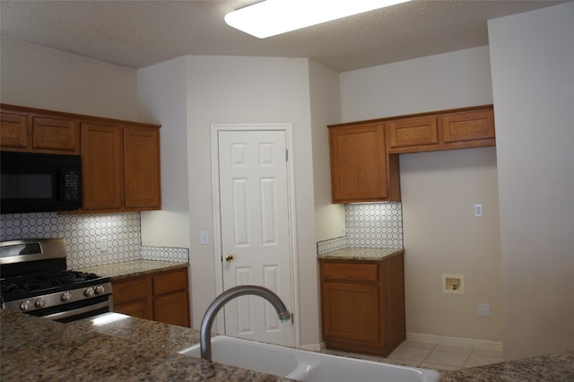 kitchen featuring light tile patterned flooring, sink, a textured ceiling, stainless steel gas range oven, and decorative backsplash