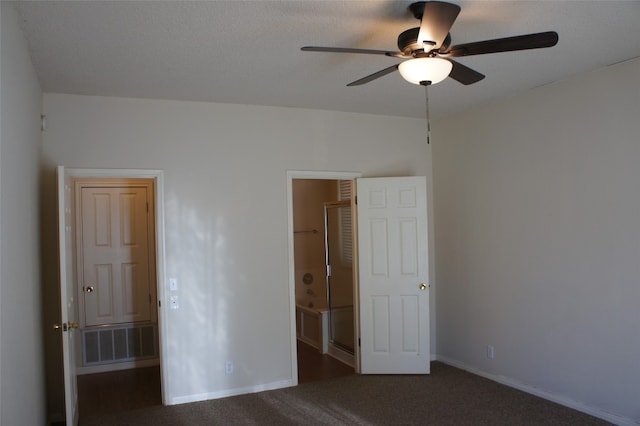 unfurnished bedroom featuring ceiling fan, dark colored carpet, and a walk in closet