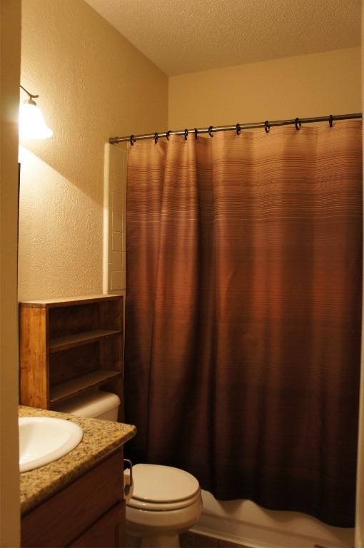 bathroom featuring vanity, toilet, and a textured ceiling