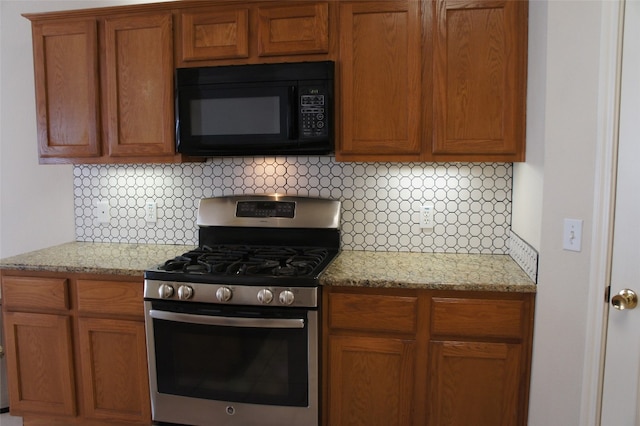 kitchen featuring light stone countertops, stainless steel gas range, and tasteful backsplash