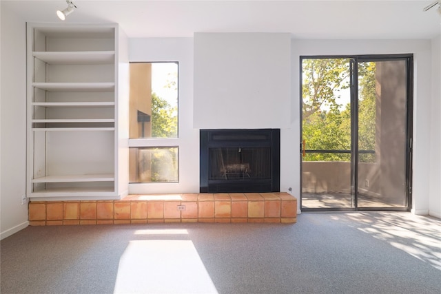 unfurnished living room with carpet floors and a tiled fireplace