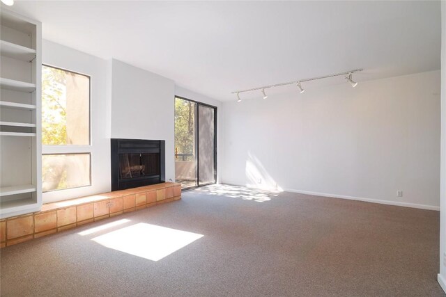 1707 Spyglass Dr Unit 57, Austin, TX 78746 - unfurnished living room with rail lighting, a tile fireplace, and carpet floors
