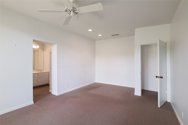 unfurnished bedroom featuring dark carpet, connected bathroom, ceiling fan, and sink