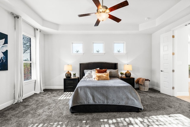 carpeted bedroom with ceiling fan and a raised ceiling