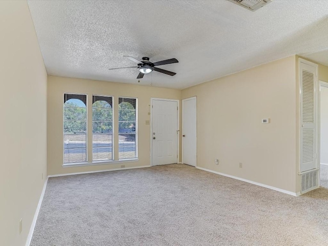 spare room featuring ceiling fan, light colored carpet, and a textured ceiling