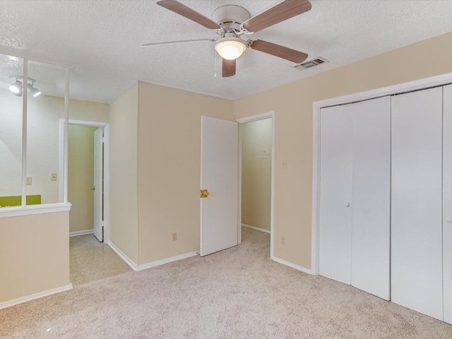 unfurnished bedroom with ceiling fan, light carpet, and a textured ceiling