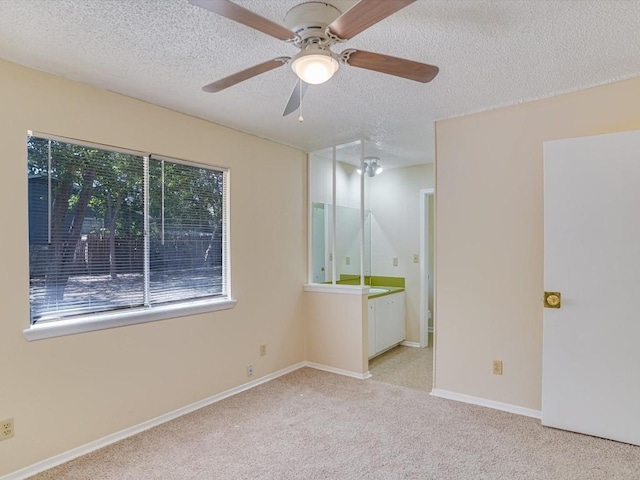 spare room with ceiling fan, light colored carpet, and a textured ceiling