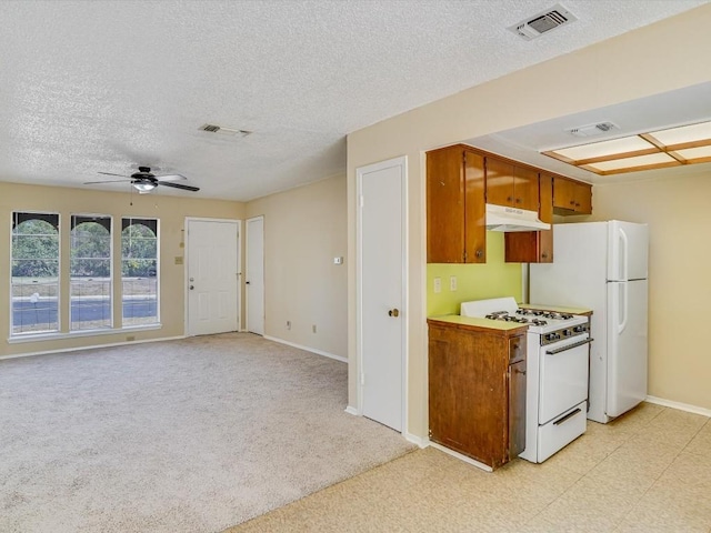 kitchen with a textured ceiling, ceiling fan, light carpet, and white appliances