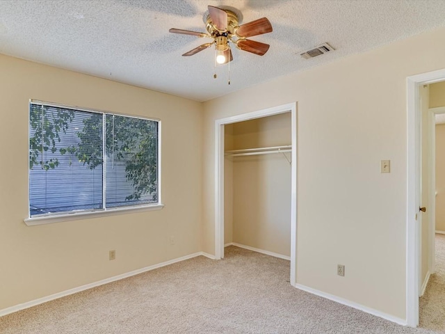 unfurnished bedroom with a textured ceiling, a closet, ceiling fan, and light colored carpet