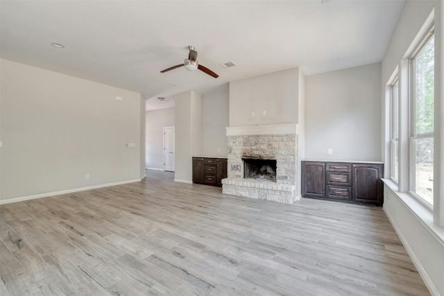 unfurnished living room with ceiling fan, light wood-type flooring, and a fireplace