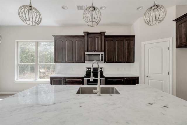 kitchen featuring decorative backsplash, stainless steel appliances, hanging light fixtures, and dark brown cabinetry