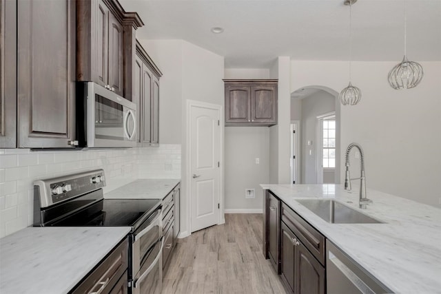 kitchen with dark brown cabinetry, light hardwood / wood-style floors, appliances with stainless steel finishes, and sink