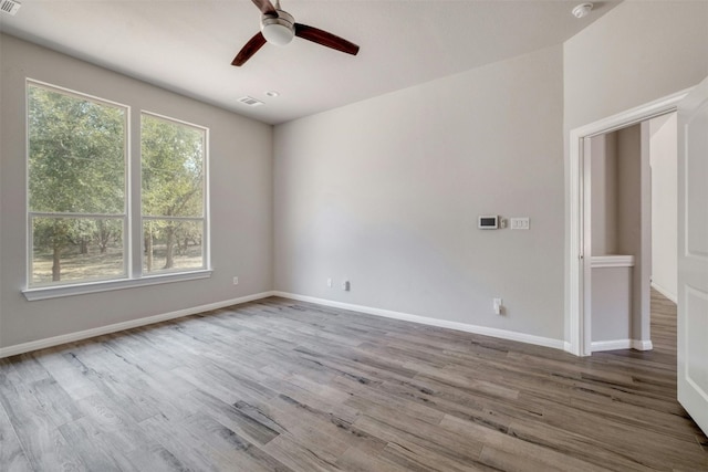 empty room featuring wood-type flooring, plenty of natural light, and ceiling fan