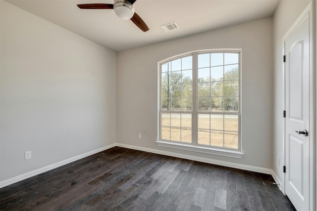 empty room featuring a healthy amount of sunlight, dark hardwood / wood-style flooring, and ceiling fan