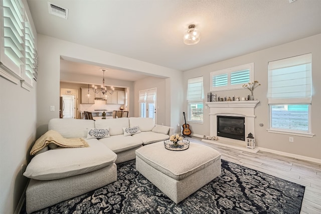 living room featuring an inviting chandelier, hardwood / wood-style flooring, and plenty of natural light