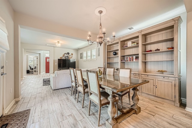 dining room with light wood-type flooring and a chandelier