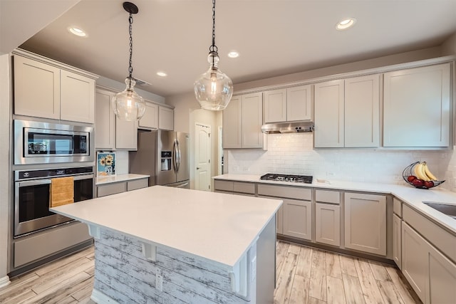 kitchen with light hardwood / wood-style flooring, backsplash, appliances with stainless steel finishes, and hanging light fixtures