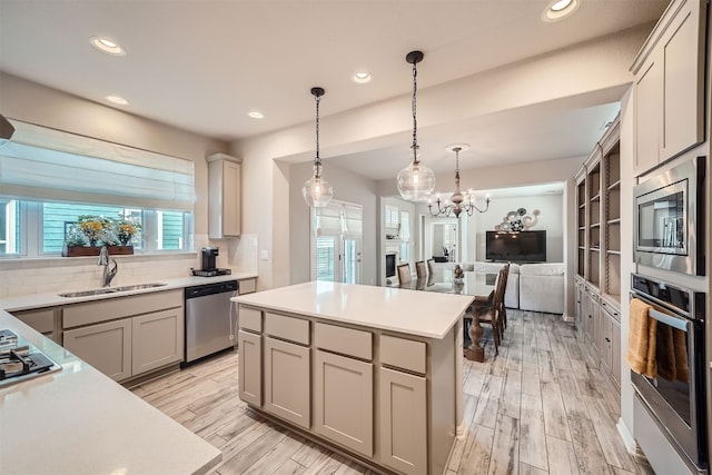 kitchen featuring gray cabinetry, backsplash, a kitchen island, stainless steel appliances, and light wood-type flooring