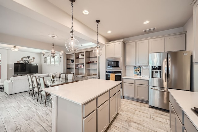 kitchen with pendant lighting, a kitchen island, gray cabinetry, light hardwood / wood-style flooring, and stainless steel appliances