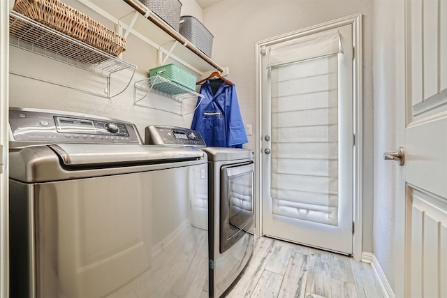 laundry room featuring separate washer and dryer and light hardwood / wood-style flooring