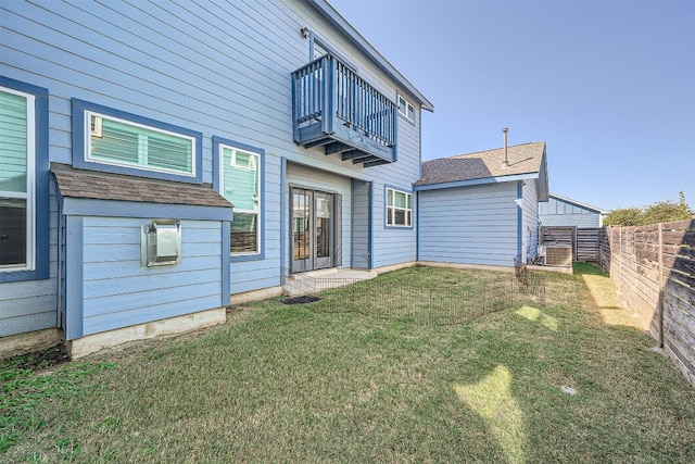 rear view of house featuring a balcony and a yard