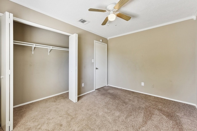 unfurnished bedroom featuring carpet, crown molding, ceiling fan, and a closet