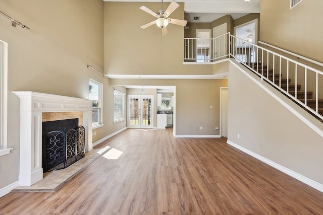 unfurnished living room featuring a high ceiling, ceiling fan, hardwood / wood-style flooring, and french doors