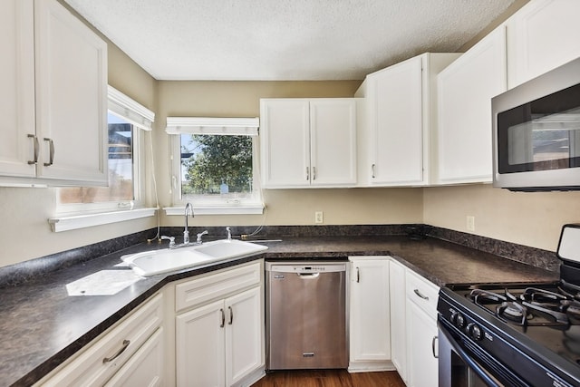 kitchen with white cabinetry, dark wood-type flooring, stainless steel appliances, a textured ceiling, and sink