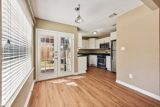 kitchen with white cabinets, stainless steel appliances, light wood-type flooring, french doors, and decorative light fixtures