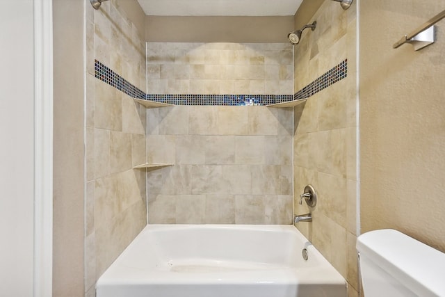 bathroom with tiled shower / bath combo and toilet