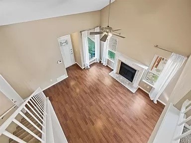 unfurnished living room with ceiling fan, dark wood-type flooring, a high end fireplace, and high vaulted ceiling