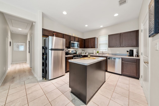 kitchen with appliances with stainless steel finishes, dark brown cabinets, a center island, and light tile patterned floors