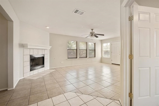 unfurnished living room featuring a tiled fireplace, ceiling fan, and light tile patterned floors