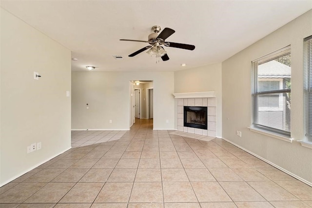 unfurnished living room with light tile patterned flooring, a tiled fireplace, and ceiling fan