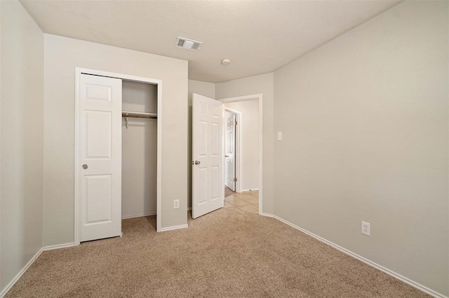 unfurnished bedroom featuring light carpet and a closet