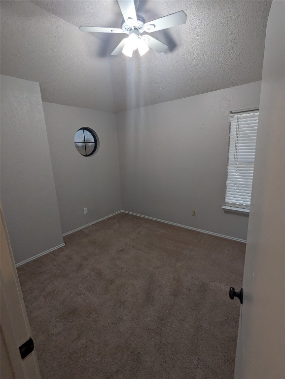 carpeted empty room with a textured ceiling, lofted ceiling, and ceiling fan