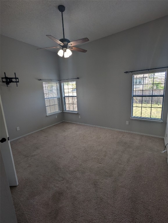 spare room featuring carpet floors, a textured ceiling, and ceiling fan