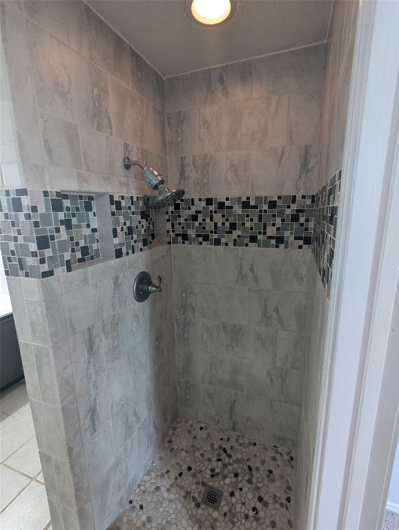 bathroom with a tile shower and tile patterned flooring