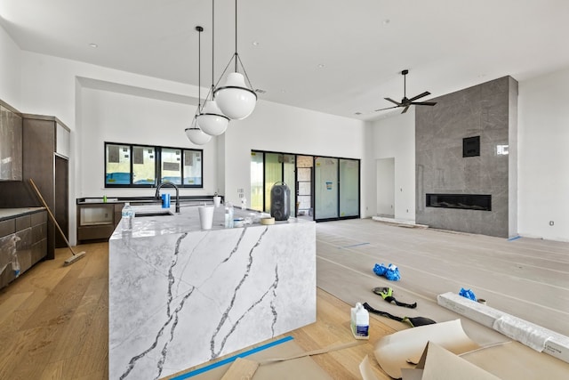 kitchen featuring pendant lighting, light hardwood / wood-style flooring, light stone countertops, ceiling fan, and a spacious island