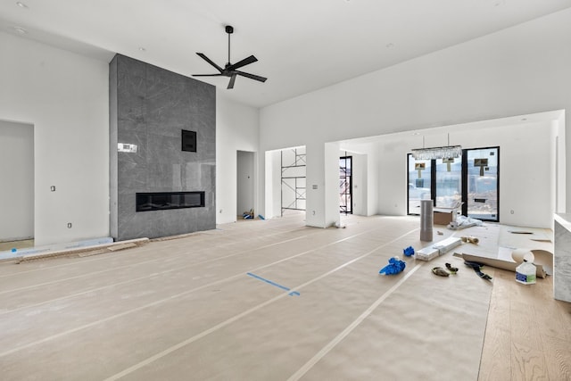 interior space featuring ceiling fan, a fireplace, light hardwood / wood-style floors, and a high ceiling